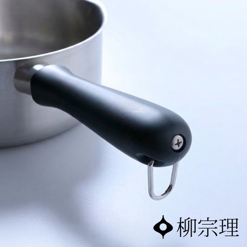 柳宗理不鏽鋼霧面單手鍋的黑色塑料把手特寫，末端設有金屬吊掛環與十字螺絲固定，下方標示著柳宗理品牌名稱。