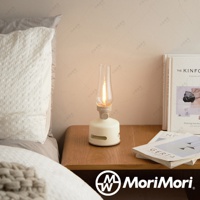 米白色煤油燈造型藍牙音響，玻璃燈罩內有LED燈模擬火焰，底部為圓柱形音響，側邊有喇叭孔，整體為簡約設計。