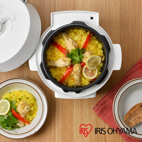 電子壓力鍋內盛放著黃色米飯、雞翅、紅椒塊、檸檬片和香草，鍋外有一個白色的壓力鍋蓋和一個裝有相似料理的白色碗。