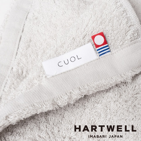 淺灰色 CUOL 今治柔彈低摩擦美肌浴巾，織紋細緻，帶有品牌標籤，材質柔軟。