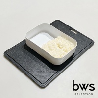 白色塑膠製食物快速冷卻盤，內有部分煮熟的白米飯，置於黑色紋理塑膠砧板上。