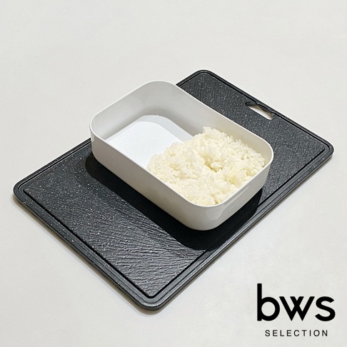 白色塑膠製食物快速冷卻盤，內有部分煮熟的白米飯，置於黑色紋理塑膠砧板上。