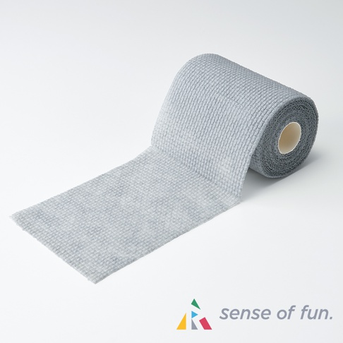 淺灰色鬆餅紋潔淨海綿巾，展開一長條，另一端捲成筒狀，質地柔軟，表面有明顯的格紋紋理。