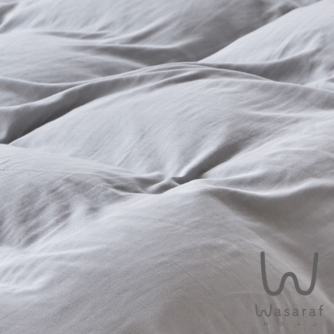 柔和的灰色床單，呈現出自然褶皺的紋理，右下方可見「Wasaraf」品牌標誌。
