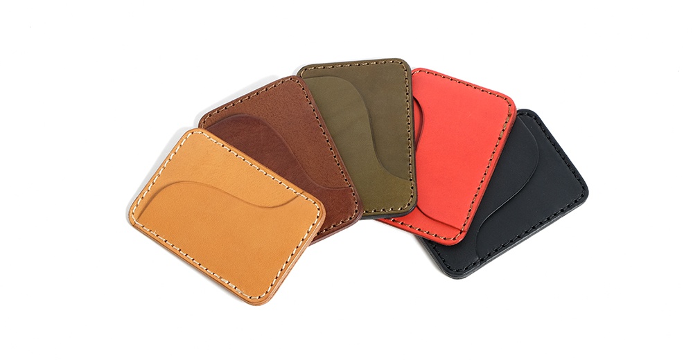 五個顏色各異的手工皮革名片夾，以扇形排列，其中包含卡其色、棕色、軍綠色、紅色和黑色。