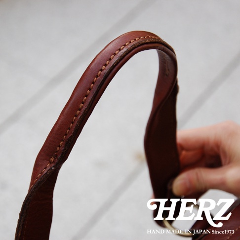 棕色皮革迷你波士頓包提把，縫線細緻，展現職人手作質感，水洗加工皮革紋理自然。