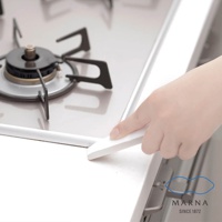 白色廚房清潔刮板，使用於不鏽鋼爐台邊緣，刮板為塑膠材質，一端呈斜角設計，方便清潔縫隙。