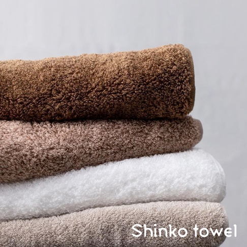 MAISON BLANC 輕奢柔膚匹馬棉浴巾，堆疊展示，顏色包括深棕、淺棕、白色及米白色，材質觸感蓬鬆柔軟。