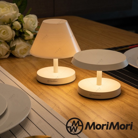 兩盞白色LED T-Light LOUNGE 工型造型燈，燈罩為圓錐形及圓盤形，底座皆為圓形，散發暖黃光，置於木質桌面，背景有白色玫瑰花束。