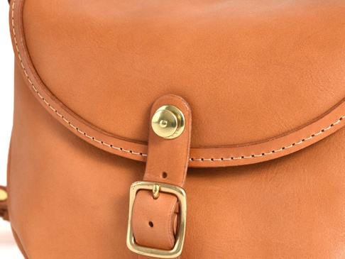 職人手作皮革休閒旅行馬鞍包 (CK-20)，採用天然皮革製成，呈現溫潤的棕褐色。包包的翻蓋處縫有細緻的白色縫線，並配有復古金屬釦環和銅色按釦，展現精緻的手工藝。