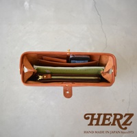 職人手作的棕色皮革Organ手拿包，內部整齊擺放著手機、卡夾、筆記本和拉鍊皮夾。