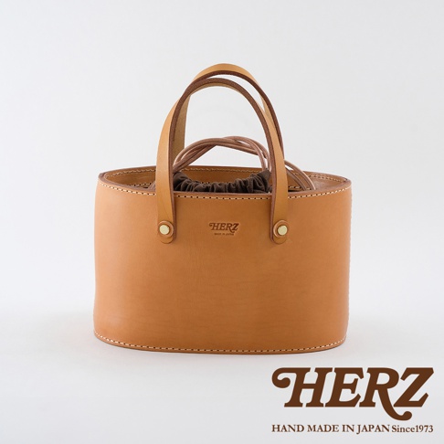 職人手作淺棕色皮革束口手提包，圓潤的包身設計，搭配雙提把與抽繩內袋，簡約大方。