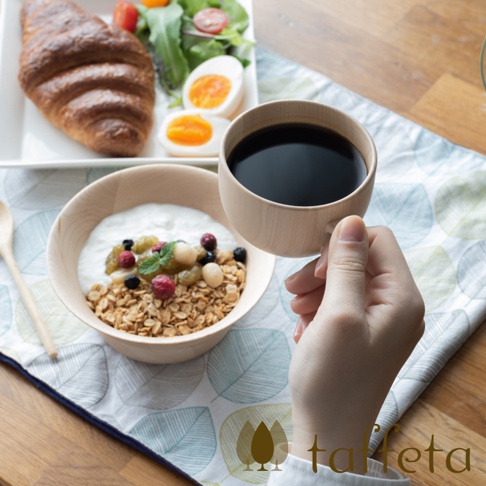 楓木製咖啡杯，盛滿深棕色咖啡，杯身呈現自然淺木色。