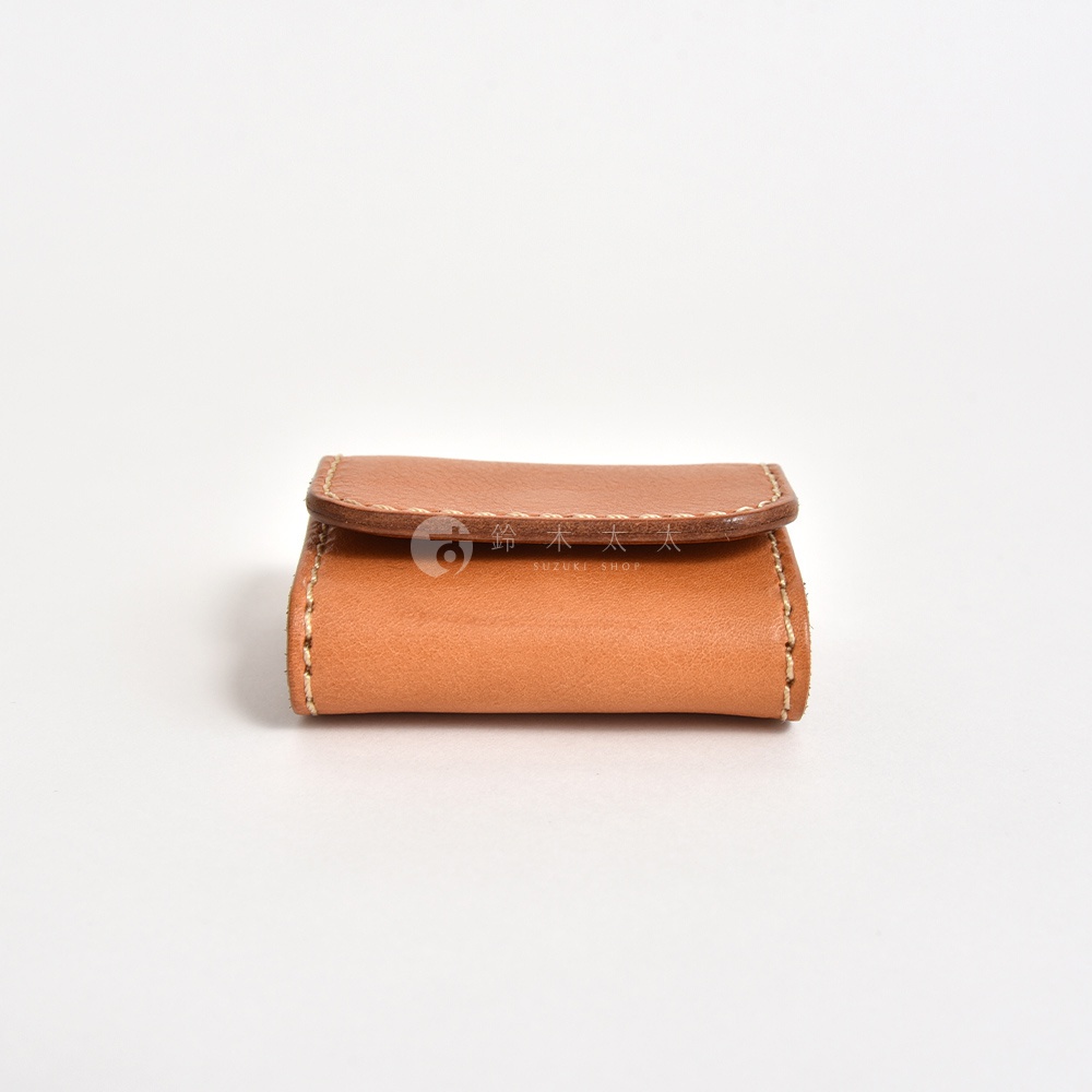 從正前方拍攝的日本HERZ職人手作皮革零錢包，呈現暖棕色調的質感皮革，外觀簡約並以手工縫線固定邊緣，中央蓋片上壓印有鈴木太太字樣，整體造型精巧細緻。