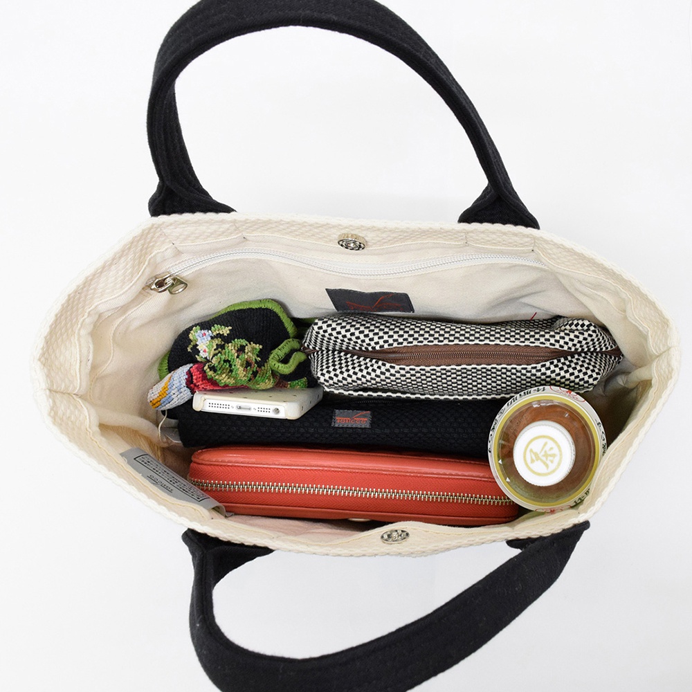 米白色帆布刺子織OBI迷你托特包，黑色提把，包內裝有手機、黑色網狀筆袋、棋盤格紋筆袋、紅色長夾和一個瓶狀物品。