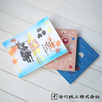 三本美濃和紙御朱印帳，分別為：藍色底、印有太陽與飛鳥圖案；粉色底、印有達摩、龜、楓葉等日式吉祥圖案；以及白色底、印有騎馬武士、楓葉與金色書法文字。