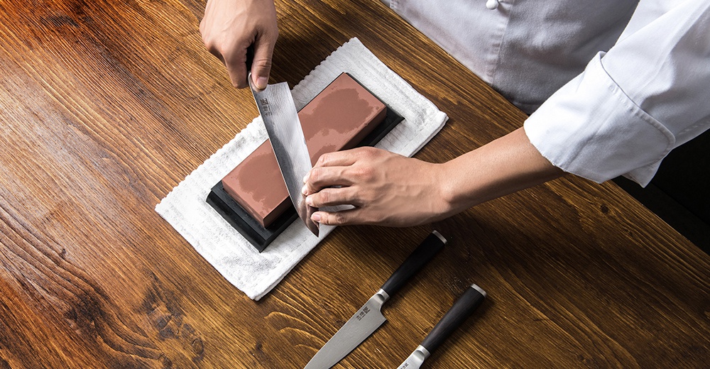 志津匠磨刀石上，雙手正為刀具打磨，桌上還有其他刀具。