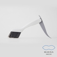 白色手柄的縫隙清潔刷，刷毛為深灰色，材質為塑膠及合成纖維。刷柄一側有淺灰色刮板設計，方便清除頑固污漬。