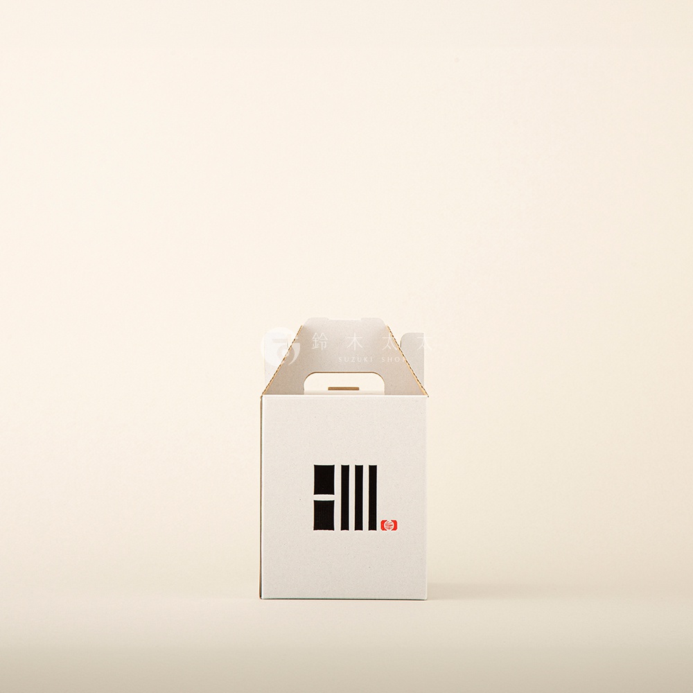 白色紙盒提燈，正面印有黑色條紋圖案與紅色印章。提把為淺棕色紙板材質。