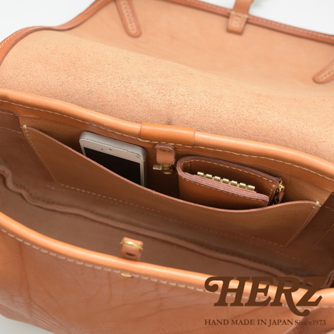 職人手作皮革大容量扣環郵差包，展示包內結構，淺棕色牛革材質，可見手機及零錢包收納夾層，做工精緻。