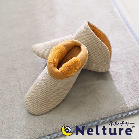 一雙淺米色格紋布面、內襯橘黃色絨毛的保暖室內拖鞋，置於灰色絨布地墊上。