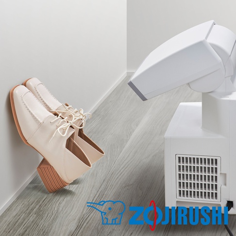 一雙米白色皮革低跟繫帶鞋，鞋頭有縫線裝飾，靠牆放置。右側為白色多功能智慧烘乾機，有可調節角度的噴嘴和側面散熱孔。