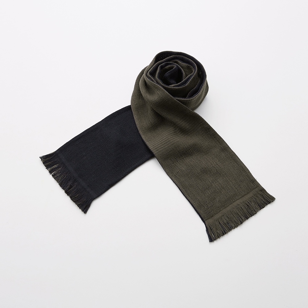 今治匹馬棉雙色圍巾，一端為黑色，另一端為軍綠色，兩側皆有流蘇裝飾，材質為針織。