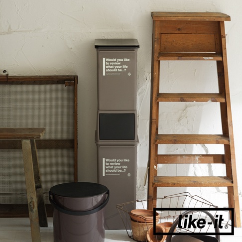 兩個疊加的灰色塑膠垃圾桶，其中一個上方有黑色前開式蓋子，上面印有白色英文文字和回收標誌。