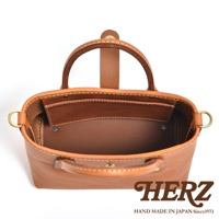 棕褐色皮革迷你托特包，頂部有提把，側面有 D 型環，內部有隔層，白色縫線，展現職人手作質感。