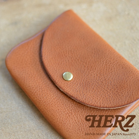 職人手作皮革小物收納袋，採用天然皮革製成，呈現溫潤的棕色調，表面有細緻紋理。鈕扣式設計，方便開合。