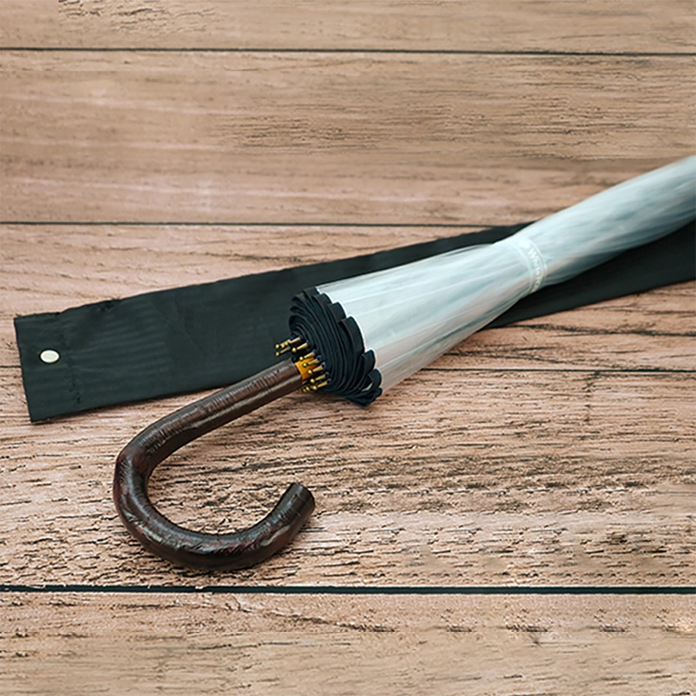 職人高級樺木透明傘，傘骨為十六櫻，傘柄為彎曲的深棕色樺木材質，傘面為透明材質，配有黑色傘套。