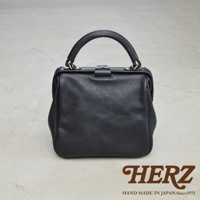 黑色皮革手提包，方形口金設計，搭配頂部提把和金屬扣環，質感柔軟。