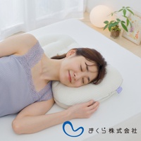 一位女性仰躺於白色床墊上，臉部朝右，頭部倚靠在一個米白色、紋理細緻的枕頭上。枕頭呈現圓潤的弧形，表面有蜂巢狀的紋路，一側有紫色品牌標籤。