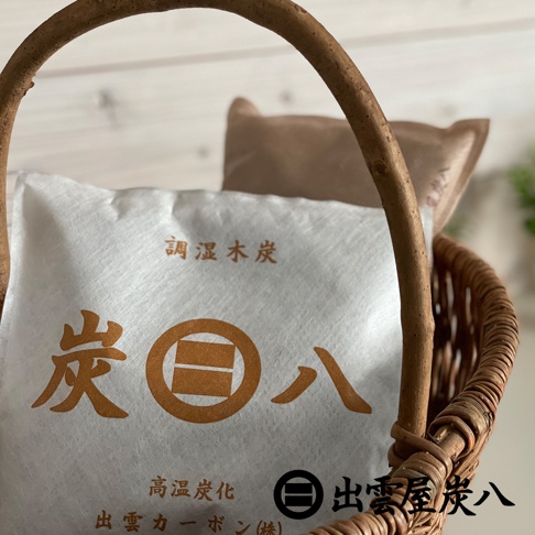 編織籃內放著一包白底褐色印刷的方形出雲屋炭八小型室內調濕木炭，包裝上印有品牌名稱與調濕木炭字樣，整體呈現簡約的居家除濕與防潮質感。