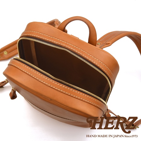 職人手作皮革長方型多口袋後背包，採用天然皮革材質，呈現溫潤的棕褐色調，主隔層拉鍊敞開，露出內部空間，縫線精緻。