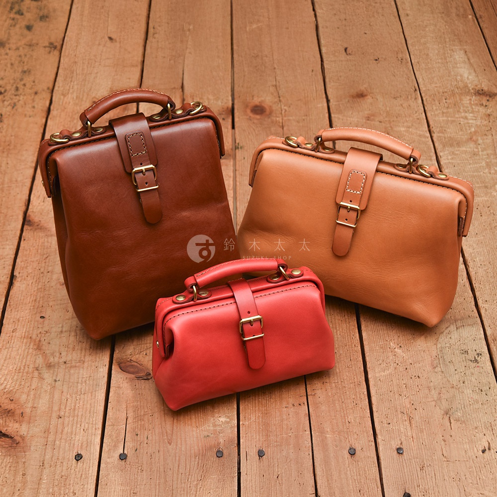 三款職人手作皮革迷你軟皮杜勒斯包，分別為棕色、駝色和紅色，皆配有金色扣環和手提帶，展現精緻工藝。