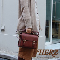 職人手作皮革迷你兩用包，深棕色，帶有雙皮帶釦設計，可手提或斜背。