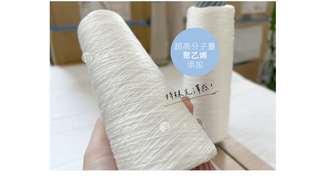 白色的嫘縈紗線纏繞在圓筒狀的軸上，紗線紋理清晰，部分紗線呈現輕微的蓬鬆感。背景有另一卷類似的紗線，以及模糊的紙箱和藍色膠帶。