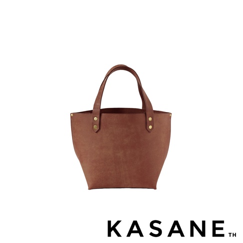 KASANE 品牌標誌下方有一個棕褐色的迷你皮革托特包，包包上有兩個短提把，並以金色鉚釘固定。