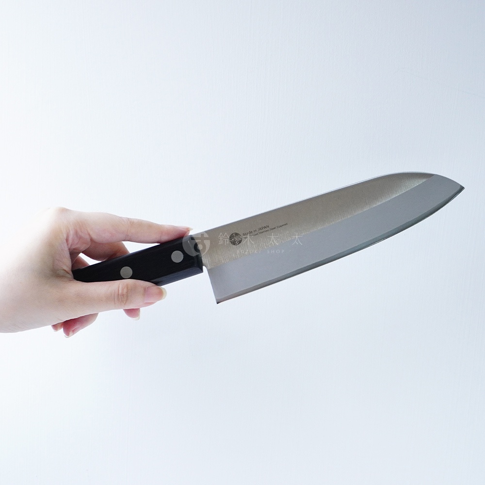 一只手持著一把燕三條 VG-10 不鏽鋼三德刀，刀刃為銀色金屬光澤，刀柄為黑色，上面有兩個鉚釘。