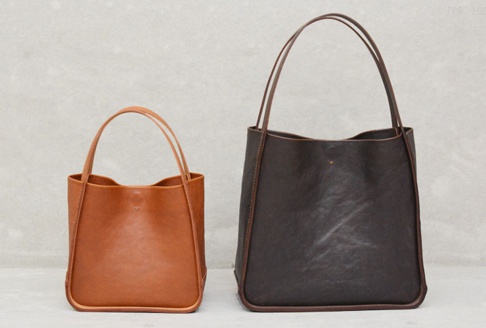 兩個職人手作皮革Organ方形托特包，一個為淺棕色，另一個為深棕色，皆採用光滑皮革材質，附有細長提把，簡約設計。