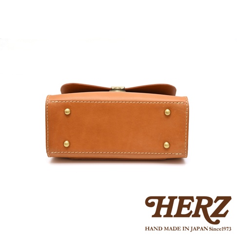 日本HERZ職人手作皮革多功能收納單肩包，以駝色牛皮革製成，配有金色底鋲，呈現簡約穩重的外觀。