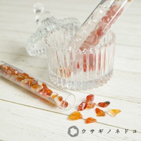 透明玻璃試管中裝有橙色和紅色的礦石碎塊，另有兩支試管和一個帶蓋的壓花透明玻璃罐。