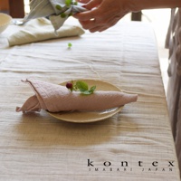 淺粉色輕柔紗布巾捲成一團，放在淺盤上，上面裝飾著一顆小草莓和幾片綠葉。