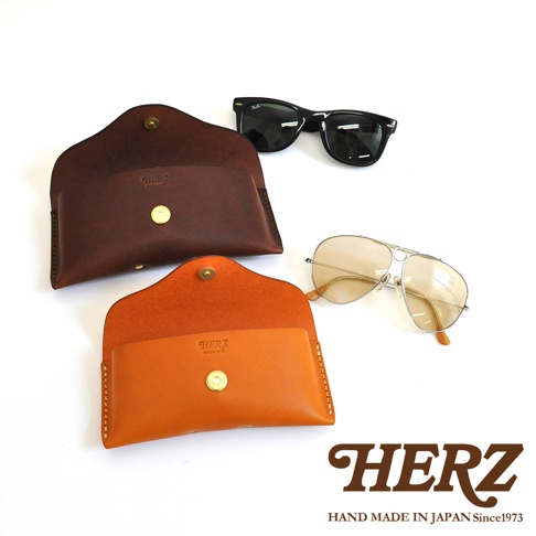 職人手作皮革眼鏡收納盒，有深棕色和亮橙色兩款，搭配兩副太陽眼鏡，其中一副為經典款黑色鏡框，另一副為飛行員款淺色鏡片。