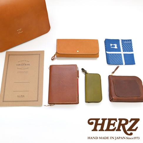 日本HERZ職人手作皮革軟皮橫式斜背包，包含一個棕色皮革筆記本、一個駝色長夾、一個褐色短夾、一個軍綠色拉鍊零錢包，以及一塊藍色印花方巾。