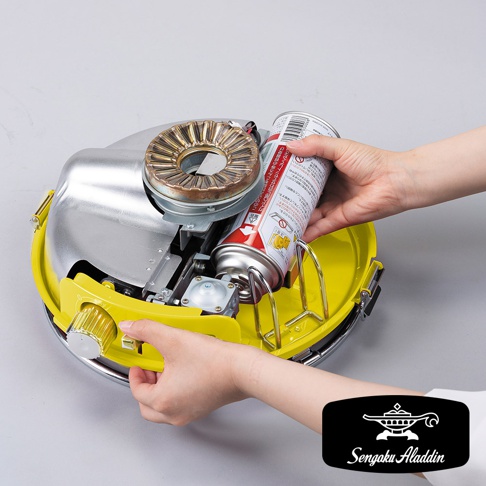 黃色與銀色卡式瓦斯暖爐，裝有瓦斯罐，爐頭為金屬材質，配備旋鈕及開關。