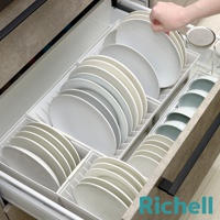 抽屜式餐盤收納架整齊擺放著白色和淺色的盤子，下方還有淺綠色的碗，整體呈現乾淨有序的廚房景象。