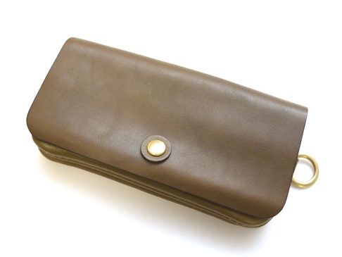 棕色皮革長夾，設有金色按扣和圓形扣環，多層次設計，適合旅行收納。