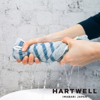 雙手正擰著一條藍白條紋的今治迷你浴巾，水從浴巾中流下。